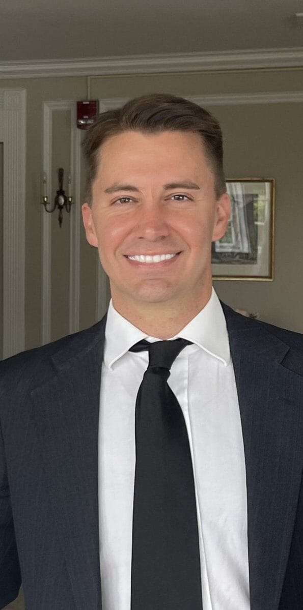 A man in a suit smiles at the camera.