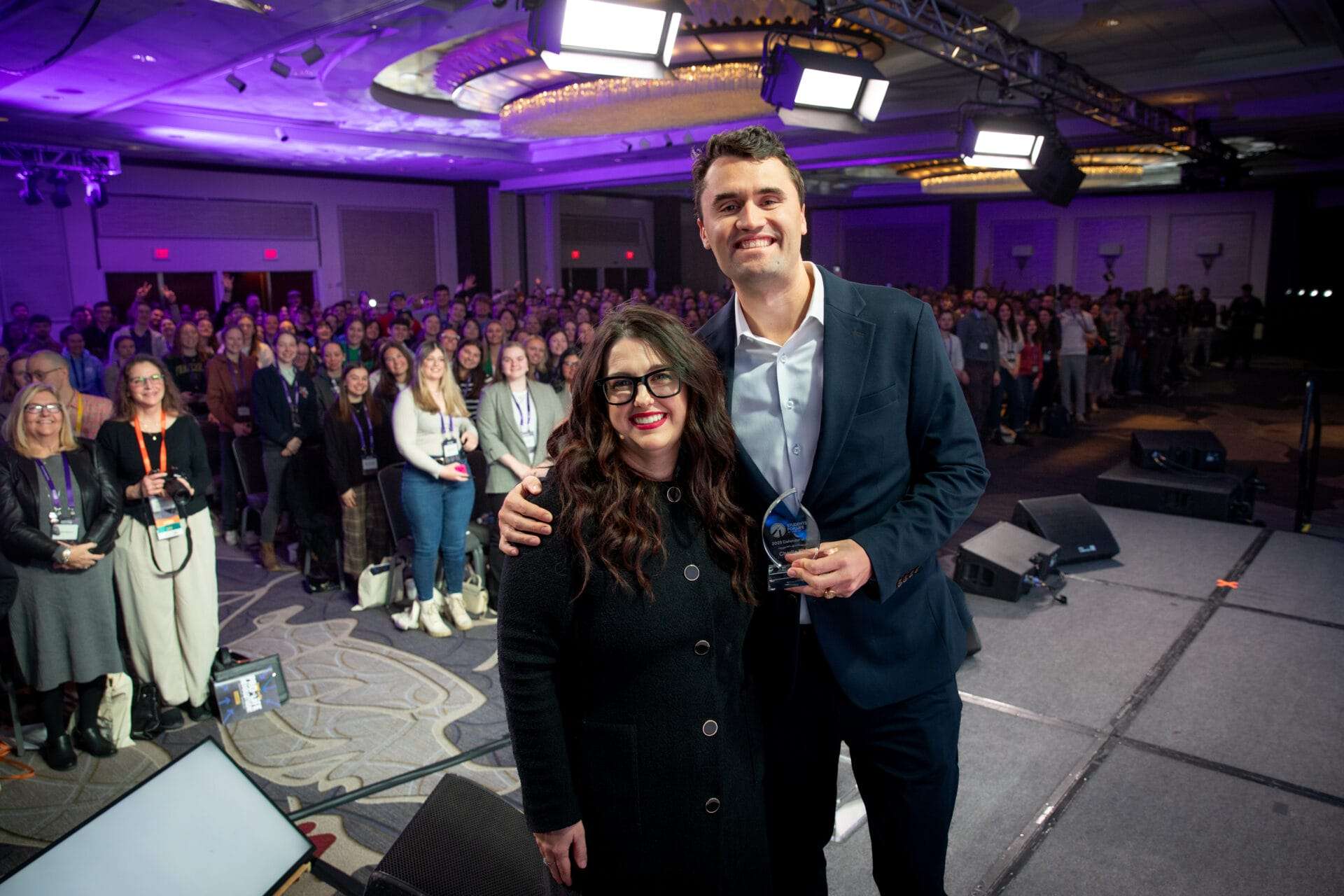 Kristan Hawkins and Charlie Kirk pose at the 2025 National Summit