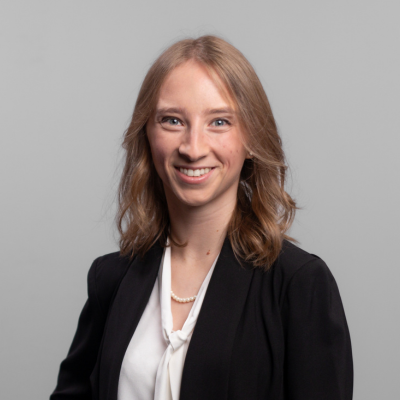 A woman in a suit smiles at the camera.