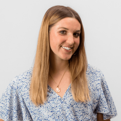 A woman turns her head to the side and smiles at the camera.