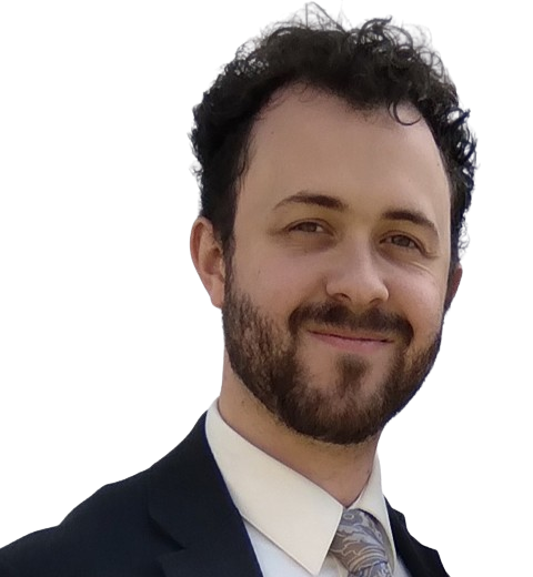 A man with a beard wears a suit and smiles at the camera.