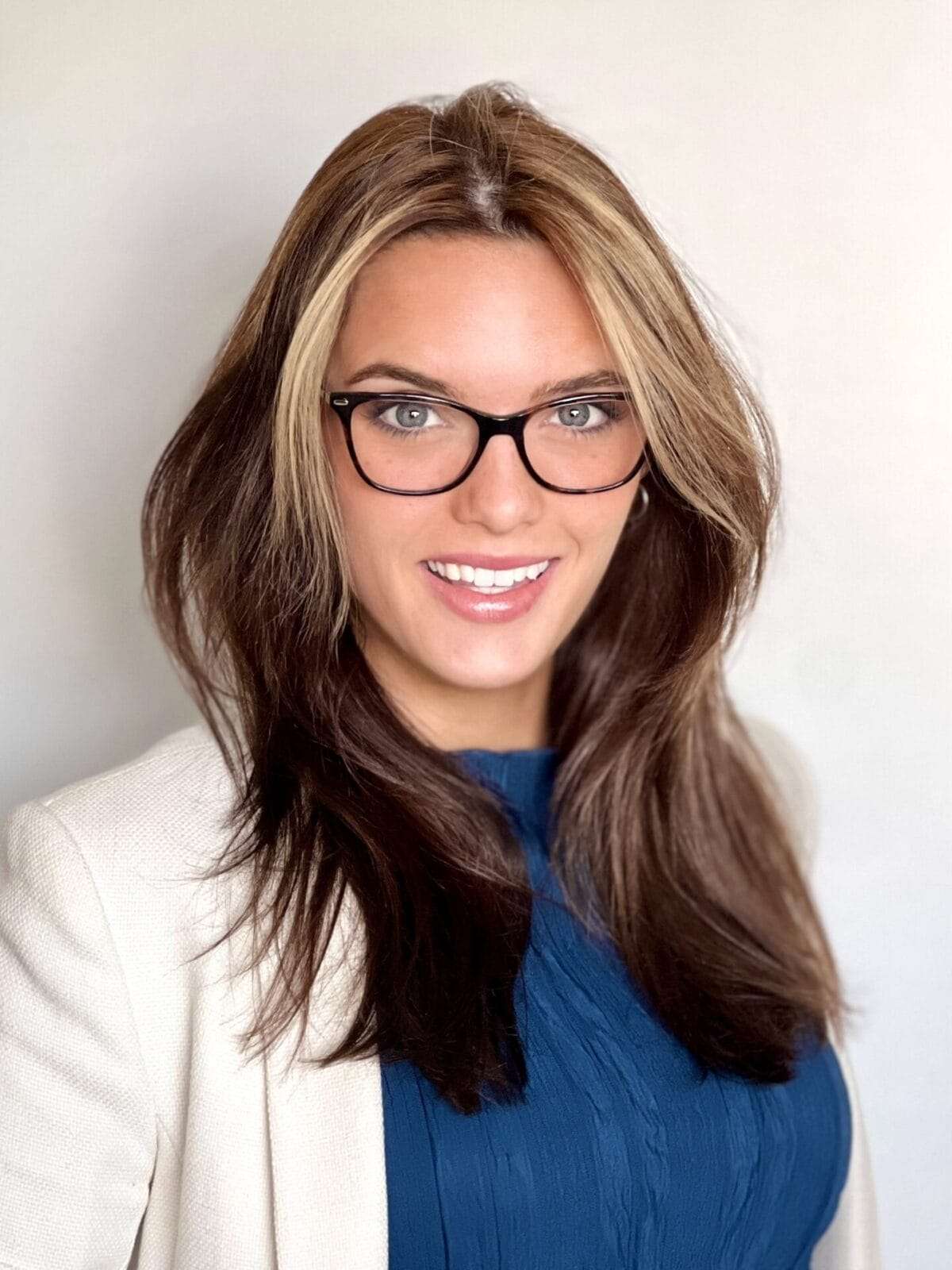 A woman wearing glasses smiles at the camera.