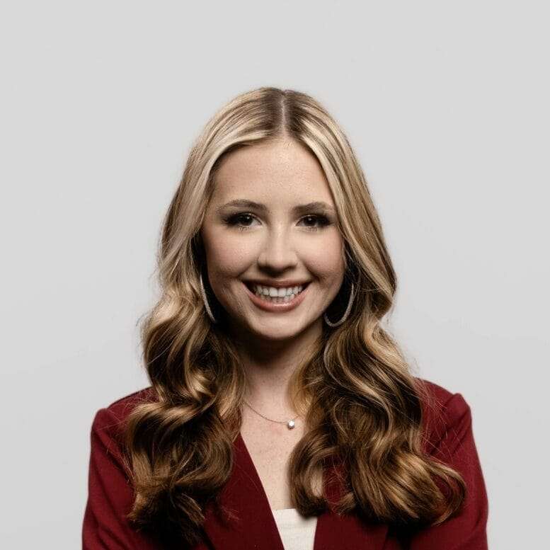 A woman with blonde hair smiles at the camera.