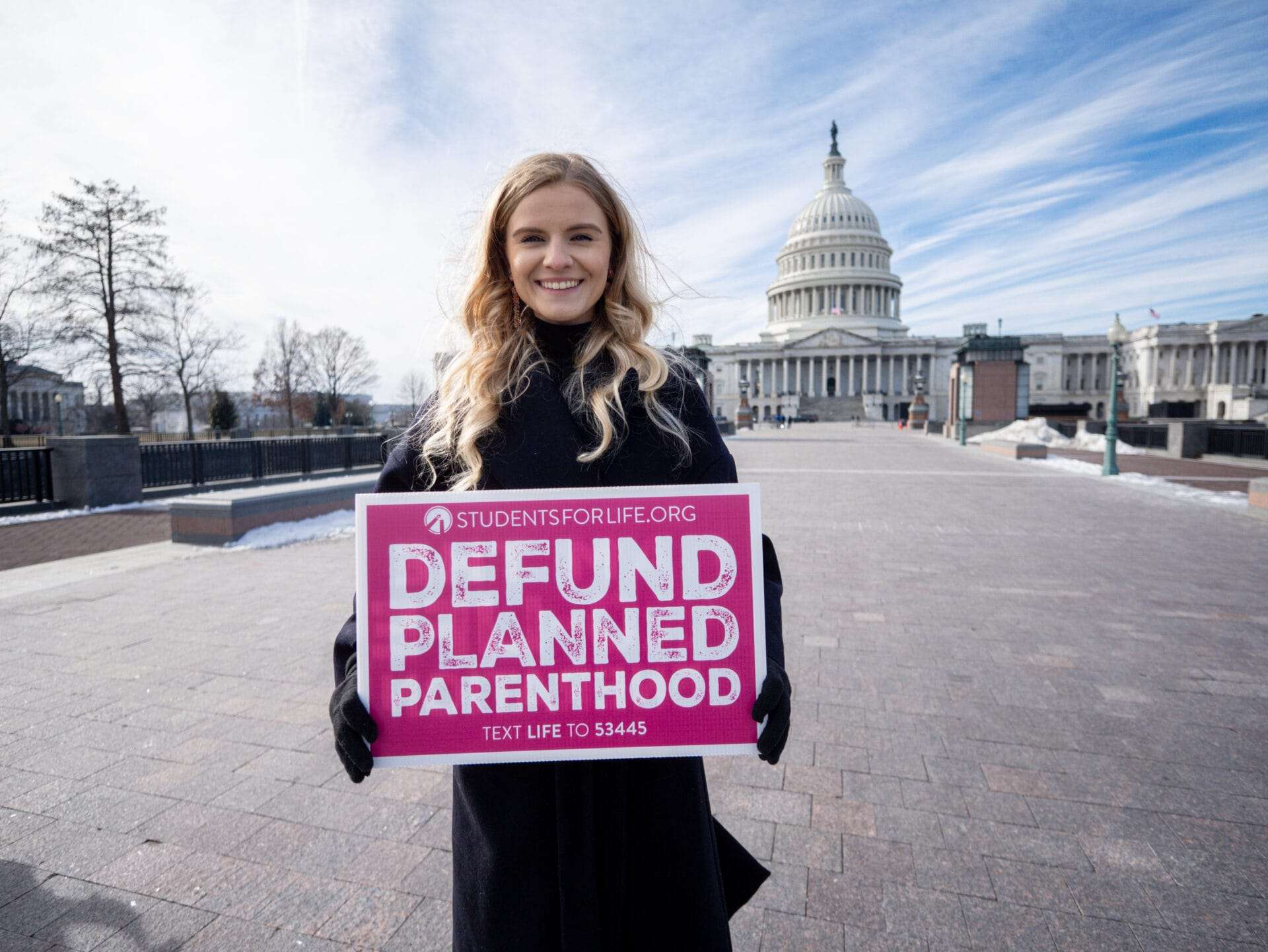 A woman holds a sign that reads, "DEFUND PLANNED PARENTHOOD" in front of the U.S. capitol.