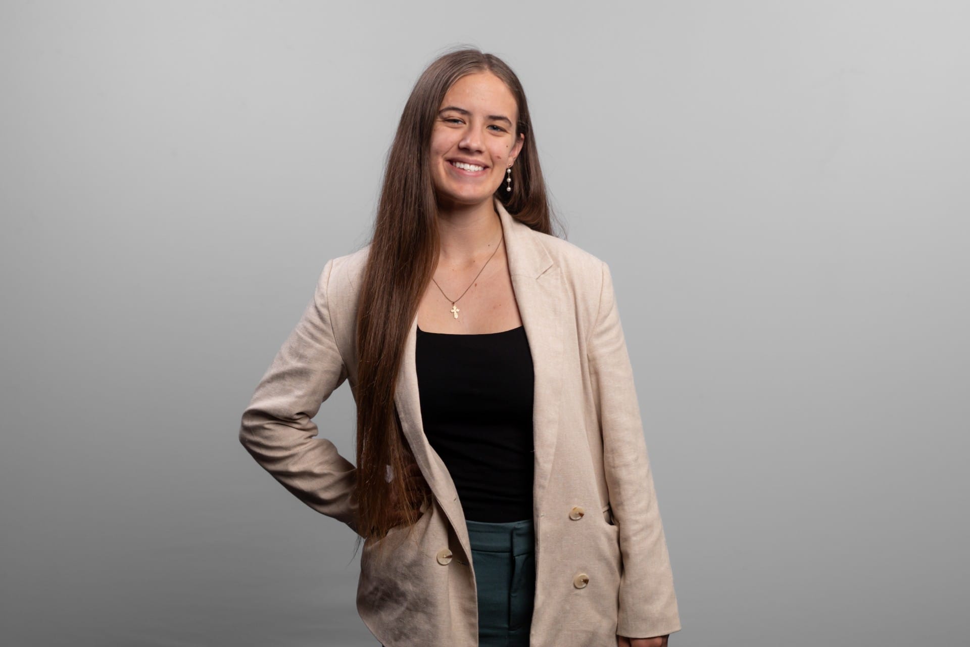 A woman stands with her hand on her hip and smiles at the camera.