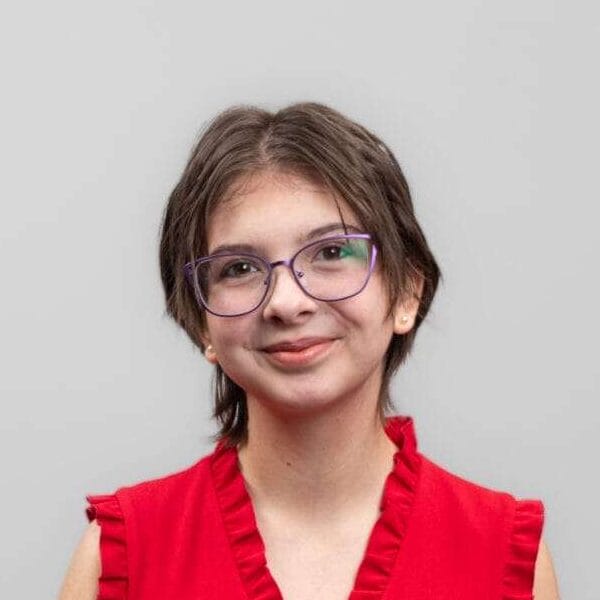 A woman with glasses smiles at the camera.