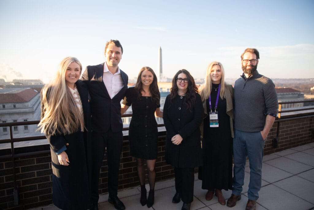 Five people stand together and smile for a photo.