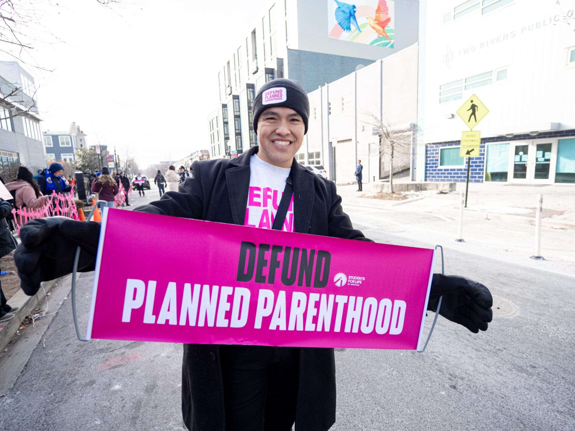 A man holds a sign that reads, "DEFUND PLANNED PARENTHOOD"